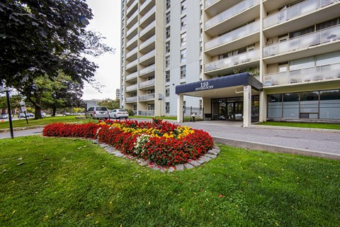 A flower bed in front of a building with the sign "110".